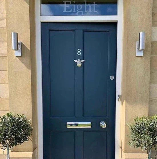 Dark blue front door with bee-shaped door knocker and silver fittings.